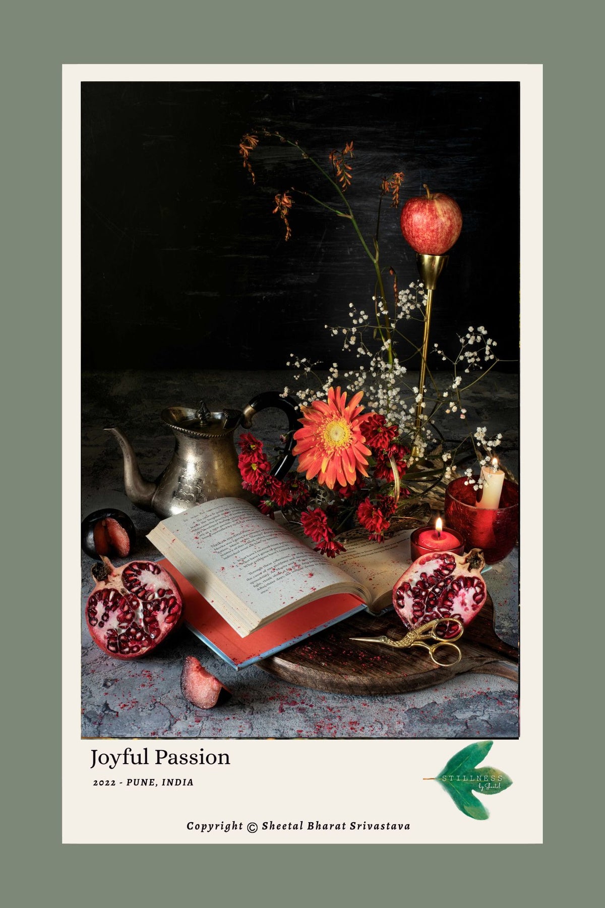 Joyful Passion (2022) - Open red book with pomegranates, silver teapot, orange gerbera, red chrysanthemums and lit candles, fine art print by Stillness by Sheetal
