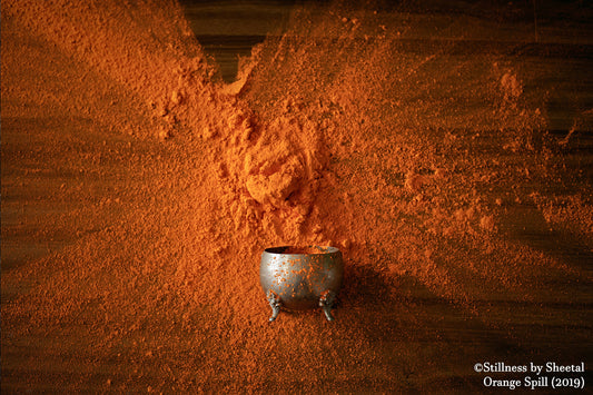 Orange Spill (2019) - Ornate silver bowl surrounded by explosive burst of orange powder on wooden surface, fine art print by Stillness by Sheetal